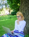 Lady freelancer working in park. Woman with laptop works outdoor, park background. Girl sit grass lean tree trunk with Royalty Free Stock Photo