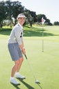 Lady golfer on the putting green at the eighteenth hole smiling at camera Royalty Free Stock Photo