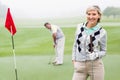 Lady golfer smiling at camera with partner behind Royalty Free Stock Photo