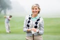 Lady golfer smiling at camera with partner behind Royalty Free Stock Photo