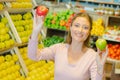 Lady in grocers holding two apples different varieties Royalty Free Stock Photo