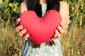 Lady hands gently raise and hold red heart with love and respect with background of nature