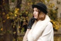 A lady in a hat, gloves and a light coat is looking out, holding her hand by the face. Retro. Outdoors. Royalty Free Stock Photo