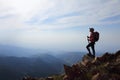 Lady hiker with backpack standing on top of the mountain