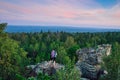 Lady hiker with backpack standing on top of the mountain and enjoying valley view at sunset Royalty Free Stock Photo