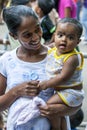 A lady holding a baby whilst waiting for the start of the Esala Perahera in Kandy, Sri Lanka.