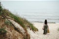 Lady with long brown hair walking to beach past little hill Royalty Free Stock Photo