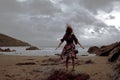 Dramatic portrait of long haired lady in floral formal dress on a stormy beach