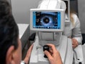 Lady looking at refractometer eye testing machine in ophthalmology
