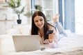 Lady lying on bed and enjoying purchase of goods on Internet using bank card.