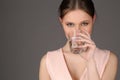 Lady with makeup drinking water. Close up. Gray background Royalty Free Stock Photo
