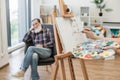 Lady making face contour of older man on canvas in workshop