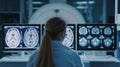 A lady medical specialist concentrates on brain images displayed on screens near MRI