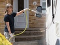 A lady motorhome owner cleans her recreational vehicle with a hose pipe.Spray can be seen coming from the pipe as lady cleans van Royalty Free Stock Photo