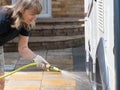 Lady motorhome owner cleaning her recreational vehicle with a hose pipe.Spray coming from the pipe as lady concentrates Royalty Free Stock Photo