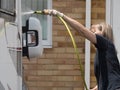 Lady motorhome owner stands cleaning her recreational vehicle with a hose pipe.Spray can be seen from the pipe Royalty Free Stock Photo