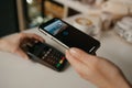 A lady paying for her latte with a smartphone by contactless PAY PASS technology