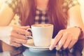 A lady picking up a cup of coffee at a coffee shop with reflections as she sits at a table