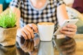 A lady picking up a cup of coffee at a coffee shop with reflections as she sits at a table