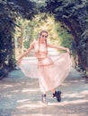 Lady with pigtails in a tutu and rough shoes stands in a curtsy pose on an alley in a summer park Royalty Free Stock Photo