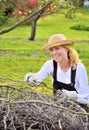 Young woman working in orchard, after tree pruning, pile of cut branches and twigs of fruit trees, cutting branches of apple trees Royalty Free Stock Photo