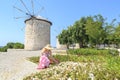 Lady in pink looking flowers among windmills in Alacati, Cesme