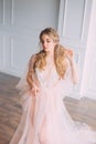 Lady in pink luxurious light dress in spacious room with white walls and bright light, gentle lace peignoir and veil Royalty Free Stock Photo