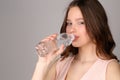 Lady in pink top drinking water. Close up. Gray background Royalty Free Stock Photo