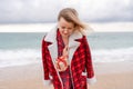 Lady in plaid shirt holding a gift in his hands enjoys beach. Coastal area. Christmas, New Year holidays concep