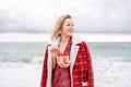 Lady in plaid shirt holding a gift in his hands enjoys beach. Coastal area. Christmas, New Year holidays concep Royalty Free Stock Photo