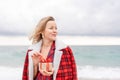 Lady in plaid shirt holding a gift in his hands enjoys beach. Coastal area. Christmas, New Year holidays concep
