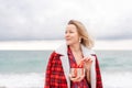 Lady in plaid shirt holding a gift in his hands enjoys beach. Coastal area. Christmas, New Year holidays concep Royalty Free Stock Photo