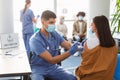 Lady Receiving Coronavirus Vaccine Injection Sitting With Doctor Indoor