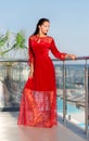 A lady in a red dress posing on a sunny resort background. An elegant young woman on a glass balcony. Glamorous Royalty Free Stock Photo