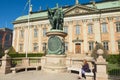 Lady relaxes at the bench in front of the House of Nobility and statue of Gustaf Eriksson Vasa in Stockholm, Sweden. Royalty Free Stock Photo