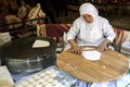 A lady rolls Turkish flat bread before placing it onto a hot plate cooker. Royalty Free Stock Photo