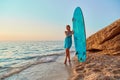 Lady on sandy coastline on sunset. Calm sea, empty beach and surfboard. Idea of summer time and surfing, copy space Royalty Free Stock Photo