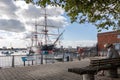 Lady seated on a bench in front of HMS Warrior, Britain`s first iron-hulled, armoured battleship, moored at Portsmouth Dockyard, H