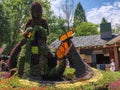 Lady sewing coat of many colors art decoration made from plants and hanging colorful umbrellas