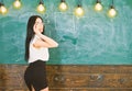 Lady teacher looking back while explaining formula. Teacher of mathematics writing on chalkboard, rear view.