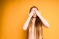 girl covers her face with her hands, portrait on an orange background Royalty Free Stock Photo