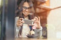 The lady sit and relax in the cafe, holding the phone in hand.