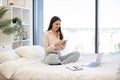 Lady sitting on bed and enjoying chatting with coworkers using smartphone. Royalty Free Stock Photo