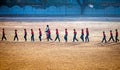 Lady sports teacher guiding children to walk in a formation on playground