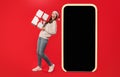 lady standing near empty phone screen holding present, red background