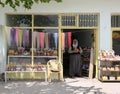 A lady stands at the doorway of her souvenir shop .