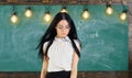 Lady strict teacher on calm face stands in front of chalkboard. Woman with long hair in white blouse stands in classroom Royalty Free Stock Photo