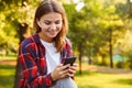 Lady student sitting in the park using mobile phone listening music. Royalty Free Stock Photo