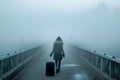 lady with suitcase walking into fog on bridge Royalty Free Stock Photo