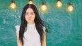 Lady teacher on calm face stands in front of chalkboard. Woman with long hair in white blouse stands in classroom. Smart